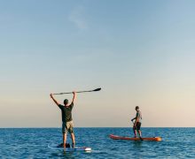 man and woman standing on blue surfboard during daytime